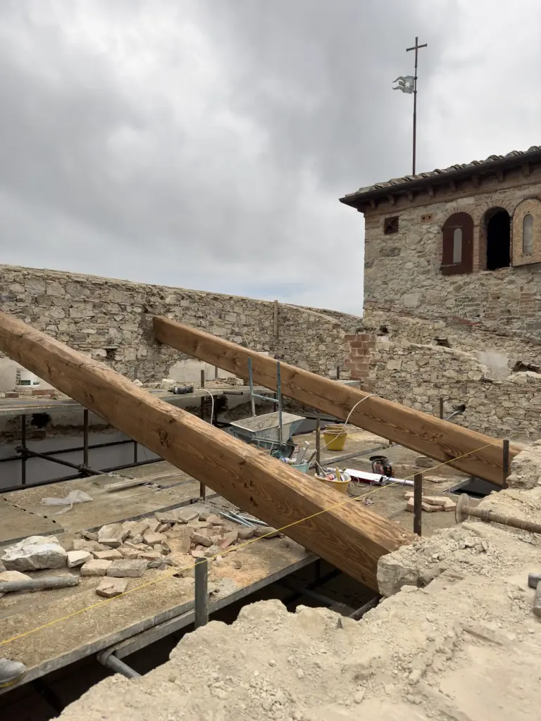 Grandi travi in legno posizionate sulle storiche murature in pietra nuda durante le delicate fasi di consolidamento strutturale eseguite da MC Moretti
